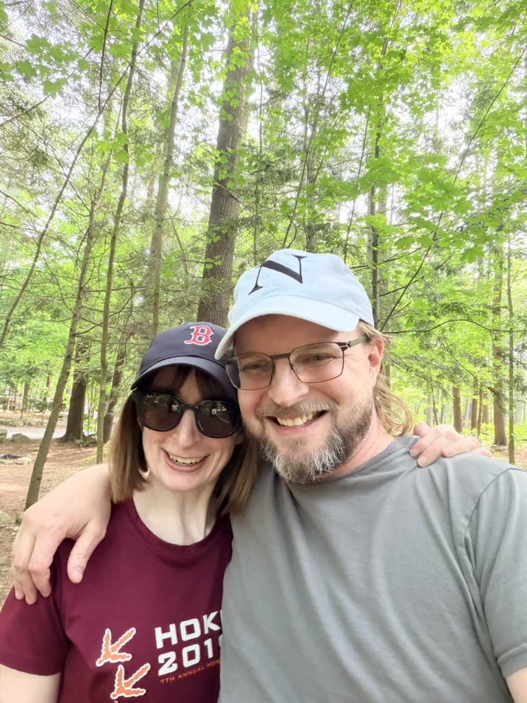 Anne and Seth smiling together in the woods